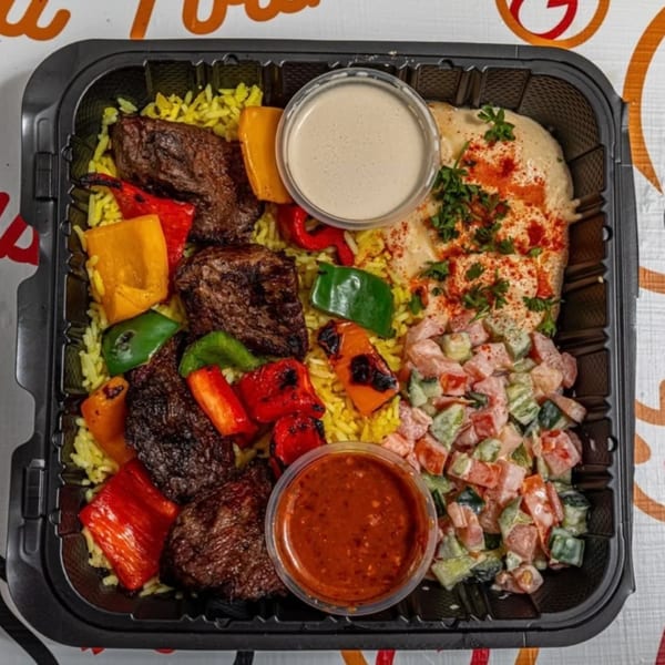 Yalla Shawarma's beef kebab plate with yellow rice, grilled peppers, hummus, salad, and sauces.